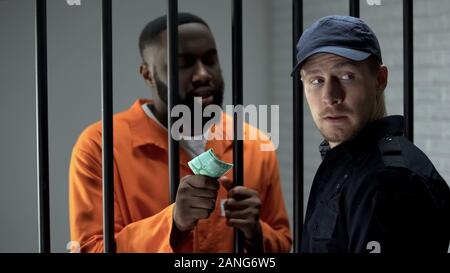 African imprigionato dando penale euro fatture da guardia carceraria, sistema difettoso Foto Stock