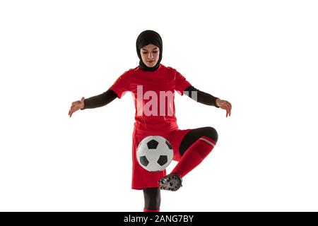 Arabian calcio femminile o giocatore di football isolato su bianco di sfondo per studio. Giovane donna calciare il pallone, formazione pratica in movimento e di azione. Concetto di sport, hobby, uno stile di vita sano. Foto Stock