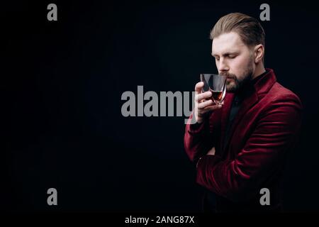 Barbuto i capelli castani uomo in giacca in velluto odore di Whiskey Foto Stock