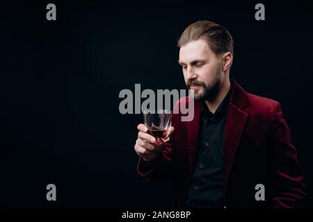 Elegante uomo in giacca in velluto guardando i suoi drink Foto Stock