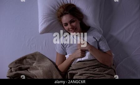 Allegra donna giaceva a letto, gioia buona novella, sensazione di eccitazione, top-view Foto Stock