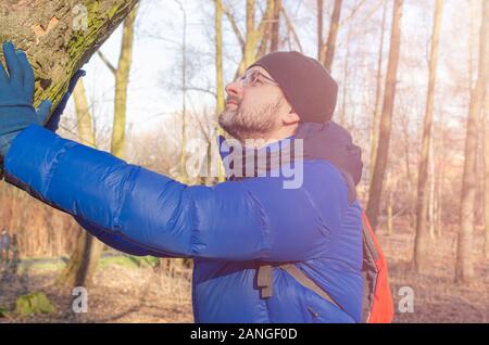 Uomo di mezza età in un fantoccio blue Down Jacket rilassante nella foresta Foto Stock