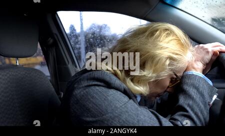 Stanco di età compresa tra i business signora seduta auto, grande città esaurimento, auto pericolo di incidenti Foto Stock