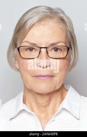 Passaporto biometrico foto di una donna senior con occhiali, sfondo grigio neutro. Foto Stock