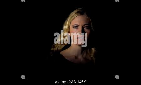 Femmina agente segreto guardando la telecamera nelle tenebre, spionaggio concetto, mistero Foto Stock