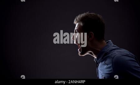 Frustrato uomo emotivamente urlando isolati su sfondo nero, problemi di vita Foto Stock