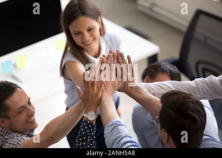 Close up sorridente ufficio giovani colleghi danno alta cinque motivato per obiettivo condiviso o di successo, eccitato i colleghi unire le mani impegnate in teambuilding Foto Stock