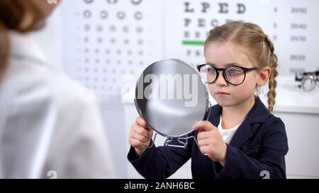 Consulente aiuta il bambino a scegliere la moda occhiali, servizio in negozio OTTICA Foto Stock