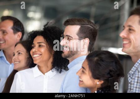 E multirazziale i colleghi millenario stand in fila sorridente che posano per una foto di gruppo, eccitato giovane diverse persone si radunano fare foto del team, motivata per sh Foto Stock