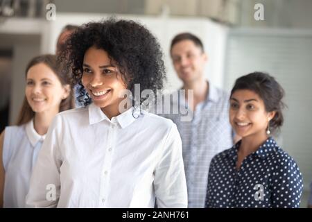 Multirazziale giovani entusiasti dipendenti stanno insieme che posano per una foto di gruppo in ufficio, millenaria diversi colleghi felice sorridente rendendo togeth foto Foto Stock