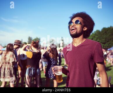 Giovane africano a bere birra al festival Foto Stock