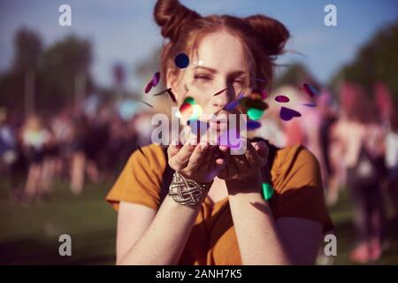 Ragazza che soffia alcuni pezzi confetti Foto Stock