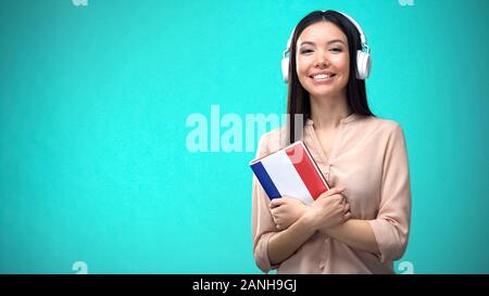 Ragazza Francese di ascolto lezioni audio in cuffia, libro in mani, traduzioni Foto Stock