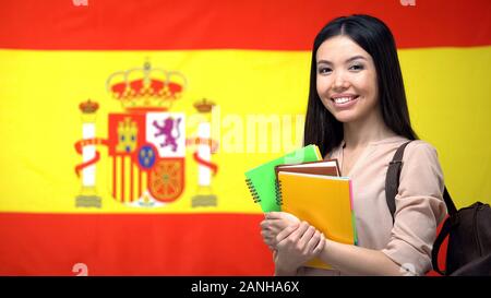 Allegro Asian studentessa in piedi contro la bandiera spagnola, lo studio della lingua Foto Stock
