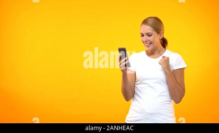 Femmina eccitato che mostra il gesto di successo di lettura messaggio sullo smartphone, offerta di lavoro Foto Stock