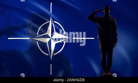 Bandiera della NATO con salutando soldato silhouette, la difesa collettiva del territorio Foto Stock