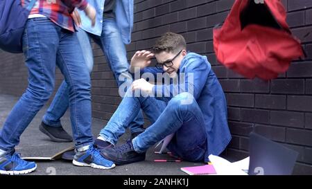 Gli studenti gettare le cose fuori di zaino sulla testa del ragazzo, teenage bullismo a scuola Foto Stock