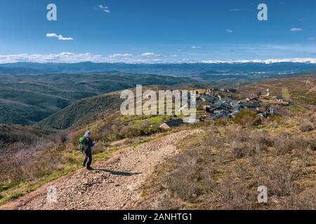 Giovane ragazza pellegrina scendendo la collina alla città di El Acebo lungo il cammino di san Giacomo (Camino de Santiago) Foto Stock