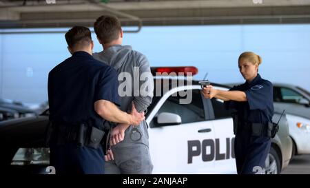 La polizia si accoppia arrestare la pericolosa PENALE, puntando la pistola, strada di prevenzione della criminalità Foto Stock