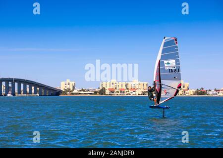 Un windsurf vola fuori dell'acqua nella parte anteriore del Ponte di Causeway nel porto di Clearwater. La temperatura è aumentata nella 80's impostazione vicino ad alta record per questo tempo di anno in Florida. Foto Stock