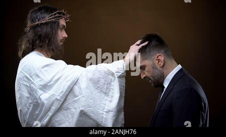 Salvatore a mettere mano sulla testa maschio, guida spirituale, amore religioso, aiutando a Dio Foto Stock