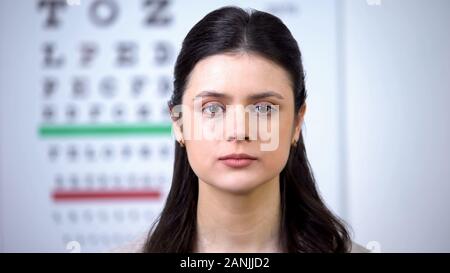 Attraente dama cercando di telecamera durante la visita all'ottico optometrista, occhi checkup Foto Stock