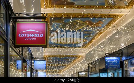 Cartello pensile per il negozio all'aperto Cotswold e le luci di Natale a Piccadilly Arcade, New Street, Birmingham, West Midlands, Inghilterra, Regno Unito Foto Stock