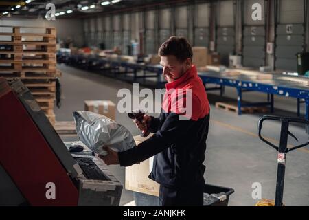 Corriere preleva il pacchetto su un magazzino Foto Stock