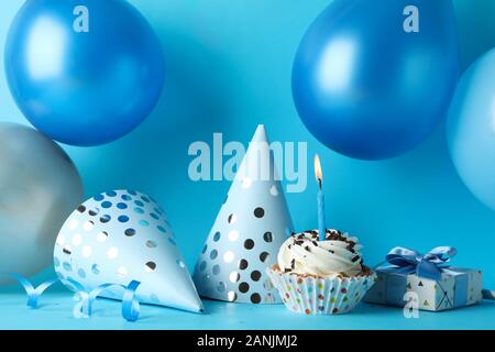 Palloncini, compleanno cappelli, cupcake e confezione regalo su sfondo blu, close up Foto Stock