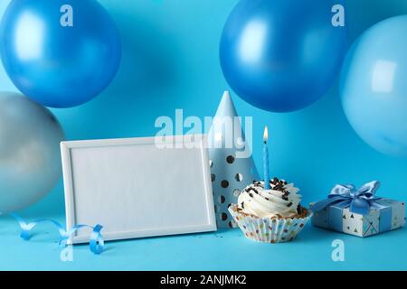 Palloncini, compleanno hat, tortina, telaio e confezione regalo su sfondo blu, spazio per il testo Foto Stock