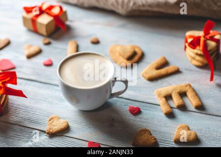 Tazza di caffè e un messaggio da un dolce cookie nella forma della parola amore su un blu sullo sfondo di legno. Romantico San Valentino dono Foto Stock