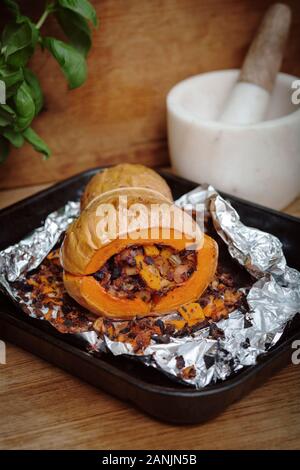 Zucca di Butternut ripiena arrosto con insalata di cavolo e ceci. Sano cibo vegano servito su un vassoio arancione con sfondo nero. Vista dall'alto / piatto Foto Stock