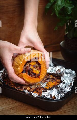 Zucca di Butternut ripiena arrosto con insalata di cavolo e ceci. Sano cibo vegano servito su un vassoio arancione con sfondo nero. Vista dall'alto / piatto Foto Stock