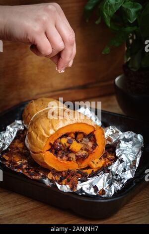 Zucca di Butternut ripiena arrosto con insalata di cavolo e ceci. Sano cibo vegano servito su un vassoio arancione con sfondo nero. Vista dall'alto / piatto Foto Stock