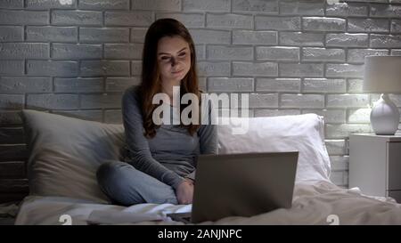 Donna sorridente la visione di film sul computer portatile, trascorrere il tempo libero, intrattenimento Foto Stock