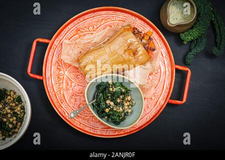 Zucca di Butternut ripiena arrosto con insalata di cavolo e ceci. Sano cibo vegano servito su un vassoio arancione con sfondo nero. Vista dall'alto / piatto Foto Stock