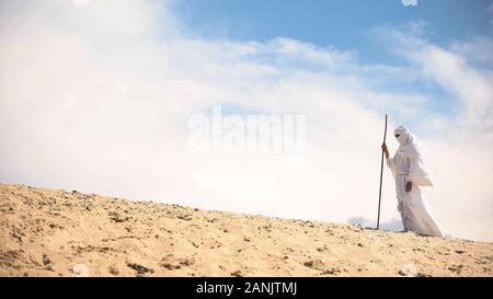 Perso il beduino con il personale a piedi nel caldo del deserto, cambiamenti climatici, della disperazione Foto Stock