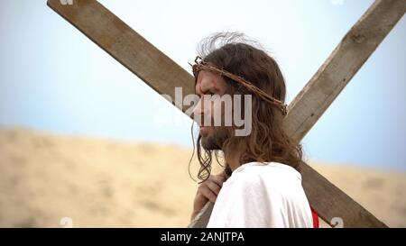 Gesù con sanguinosa fronte e corona di spine che trasportano pesante croce, la bibbia evento Foto Stock