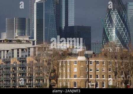 Alte proprietà finanziaria nella città di Londra che includono la Swiss Re Building, estrema destra (aka il Gherkin) salire al di sopra di moderne riverside appartamenti residenziali e la terrazza di ex funzionari dock' case (progettata da Daniel Asher Alexander) a Wapping Pierhead, costruito nel 1811-13, il 17 gennaio 2020, a Londra, in Inghilterra. Foto Stock