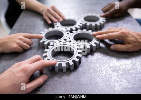 Un gruppo di imprenditori di unire insieme ingranaggi sul tavolo al posto di lavoro Foto Stock