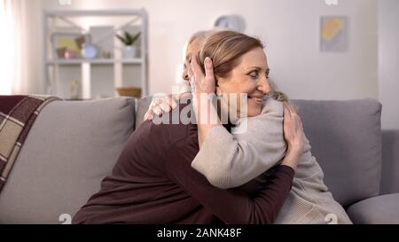 Due donne mature avvolgente seduta sul divano nel soggiorno, suore amore, famiglia Foto Stock
