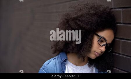 Triste adolescente africana occhiali parete pendente, problema della disperazione, insicurezze Foto Stock