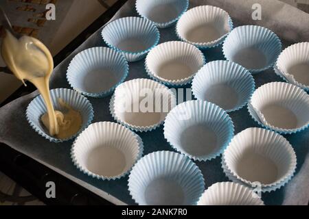 Il riempimento con la pasta della carta stampi per rendere muffin fatti in casa Foto Stock