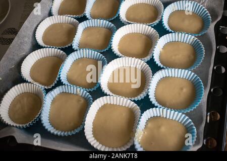 Carta cupcake stampi riempiti con impasto pronto a mettere in forno Foto Stock