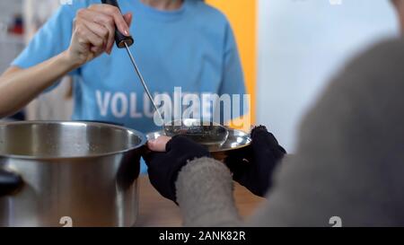 Progetto di beneficenza, femmina volontario che serve la zuppa in shelter, cura dei poveri Foto Stock