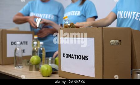 Gli attivisti femmina la preparazione di fornitura scatole, mettendo il cibo in contenitori di cartone Foto Stock