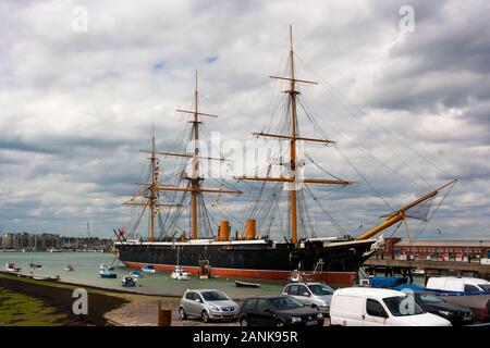 Il 9 giugno 2016 HMS Warrior si siede presso la banchina a Portsmouth dockyard lungo con le tante piccole imbarcazioni che siedono sui loro ormeggi Foto Stock