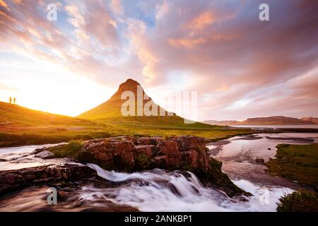 Vista epica di Kirkjufell vulcano con una piccola figura umana. Popolare e una stupenda scena. Ubicazione Kirkjufellsfoss, gite turistiche in Europa. Splendida imag Foto Stock