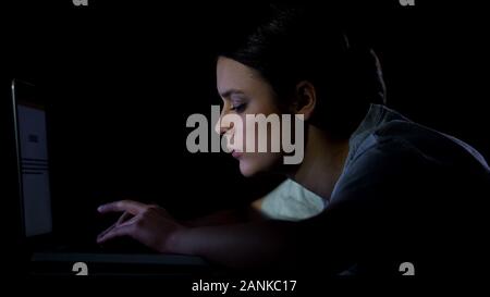 Studentessa digitando su laptop di notte, lavorando sul progetto di diploma, lavoro Foto Stock