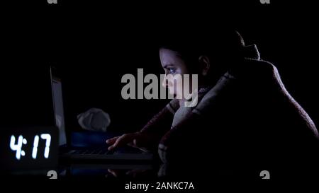 Malati lady freelance lavorando sul computer portatile di notte, prendere freddo, avvolti in plaid Foto Stock